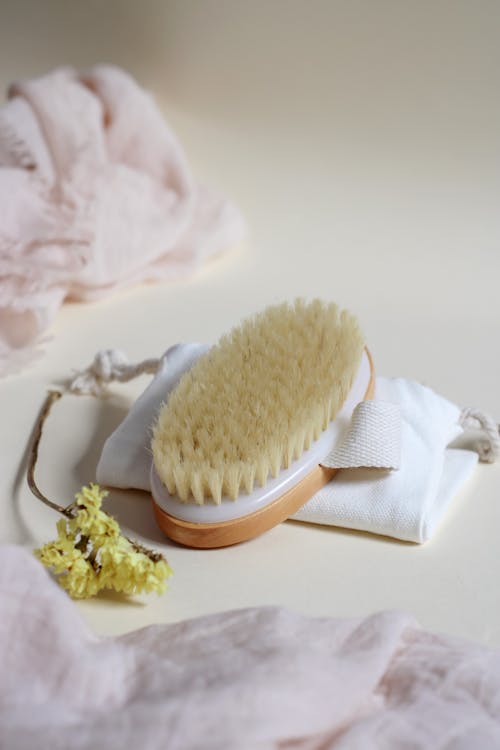 A Body Brush on a Pouch Beside a Flower