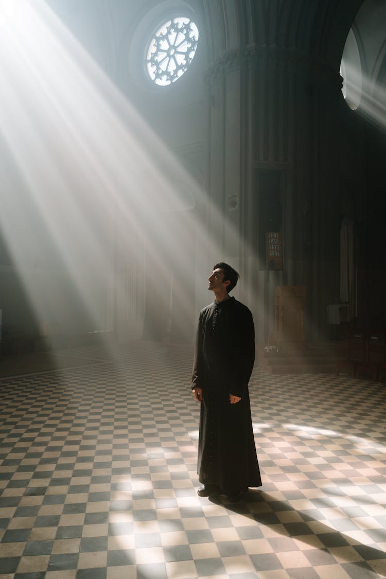 Man In Black Cassock Standing In The Cathedral