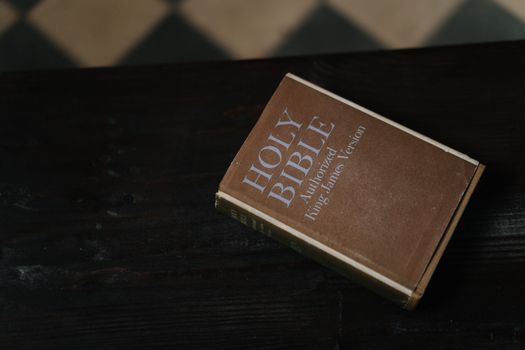 Close-up of Holy Bible resting on a dark wooden table, symbolizing faith and spirituality.