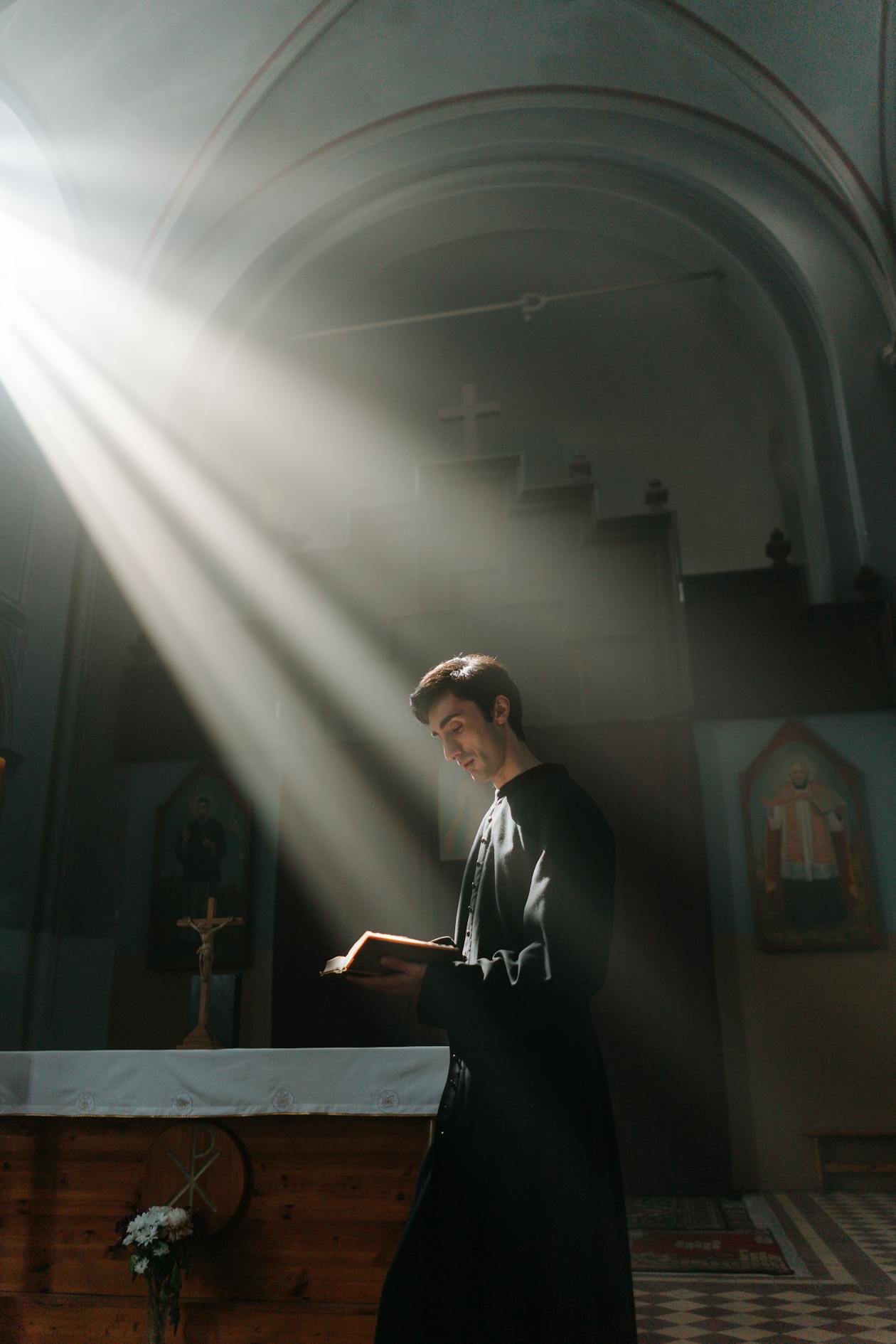 A priest reading the Bible at a church altar standing in a ray of golden light coming through a window, symbolizing spiritual illumination and divine intimacy