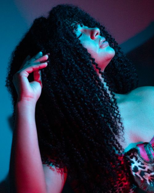 Free Artistic portrait of a woman with curly hair, illuminated by neon lighting, posing with eyes closed. Stock Photo