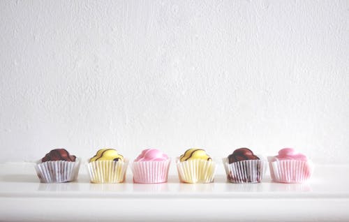 Free Six Cupcakes Near White Wall Stock Photo