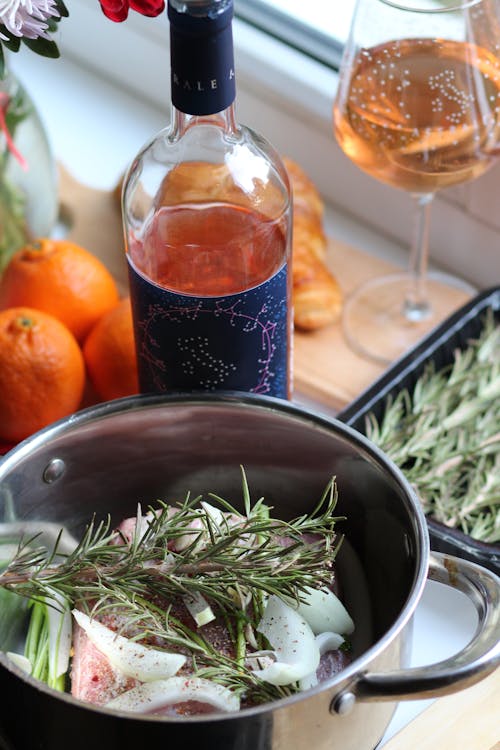 Meat with Onion and Herbs in a Pot and a Bottle of Alcohol 