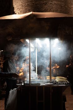 Smokey night scene of a street food vendor grilling corn in vibrant Istanbul.