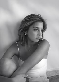 Black and white portrait of a woman in a spaghetti strap top, expressing contemplation.
