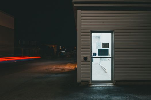 A modern building entrance at night, showcasing light contrasts and urban mood.