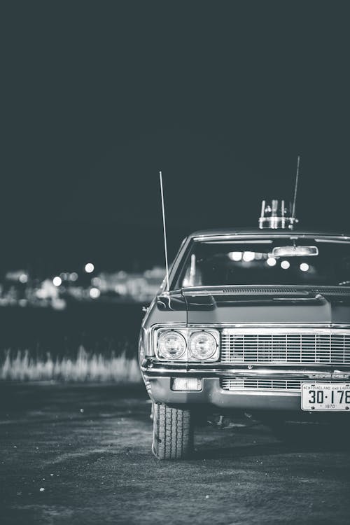 Grayscale Photo of a Vintage Car Parked on the Road