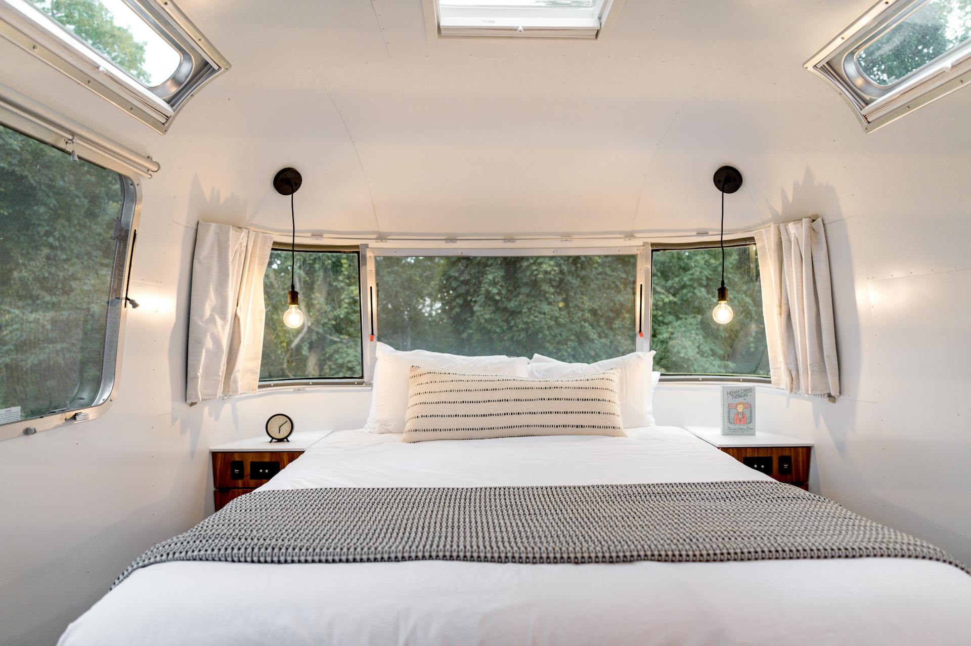 A comfortable bed setup in a stylish airstream trailer, offering a cozy glamping experience.