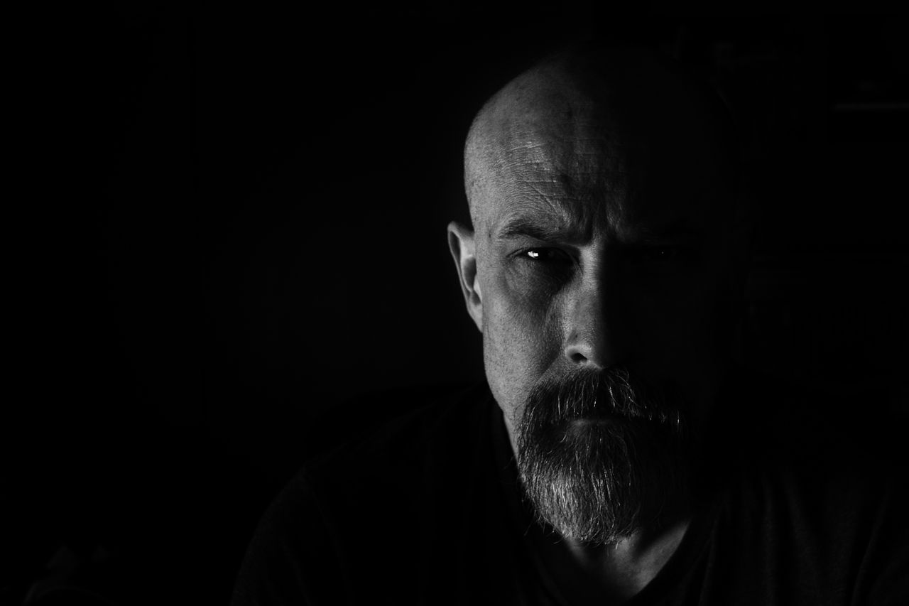 striking black and white portrait of a serious man with a beard in dra