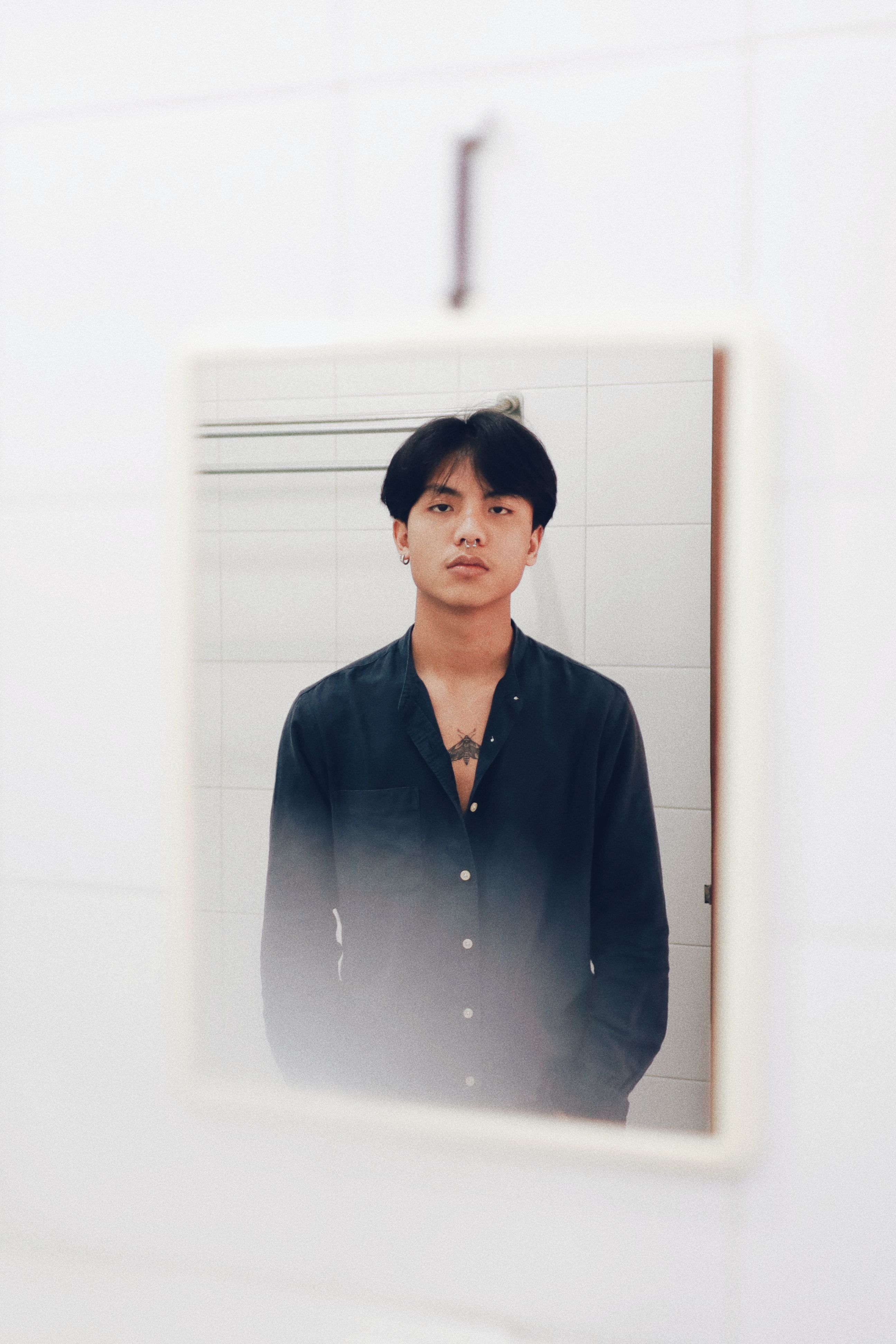 A contemplative portrait of a young adult reflected in a bathroom mirror in Yogyakarta.