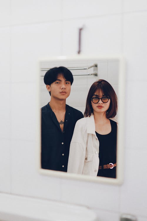 A Mirror Image of a Couple Near a Towel Rack