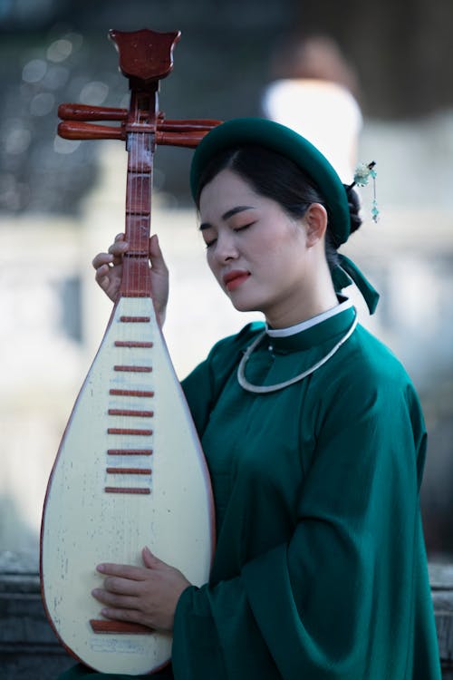 A Woman in Green Dress Holding a Pipa