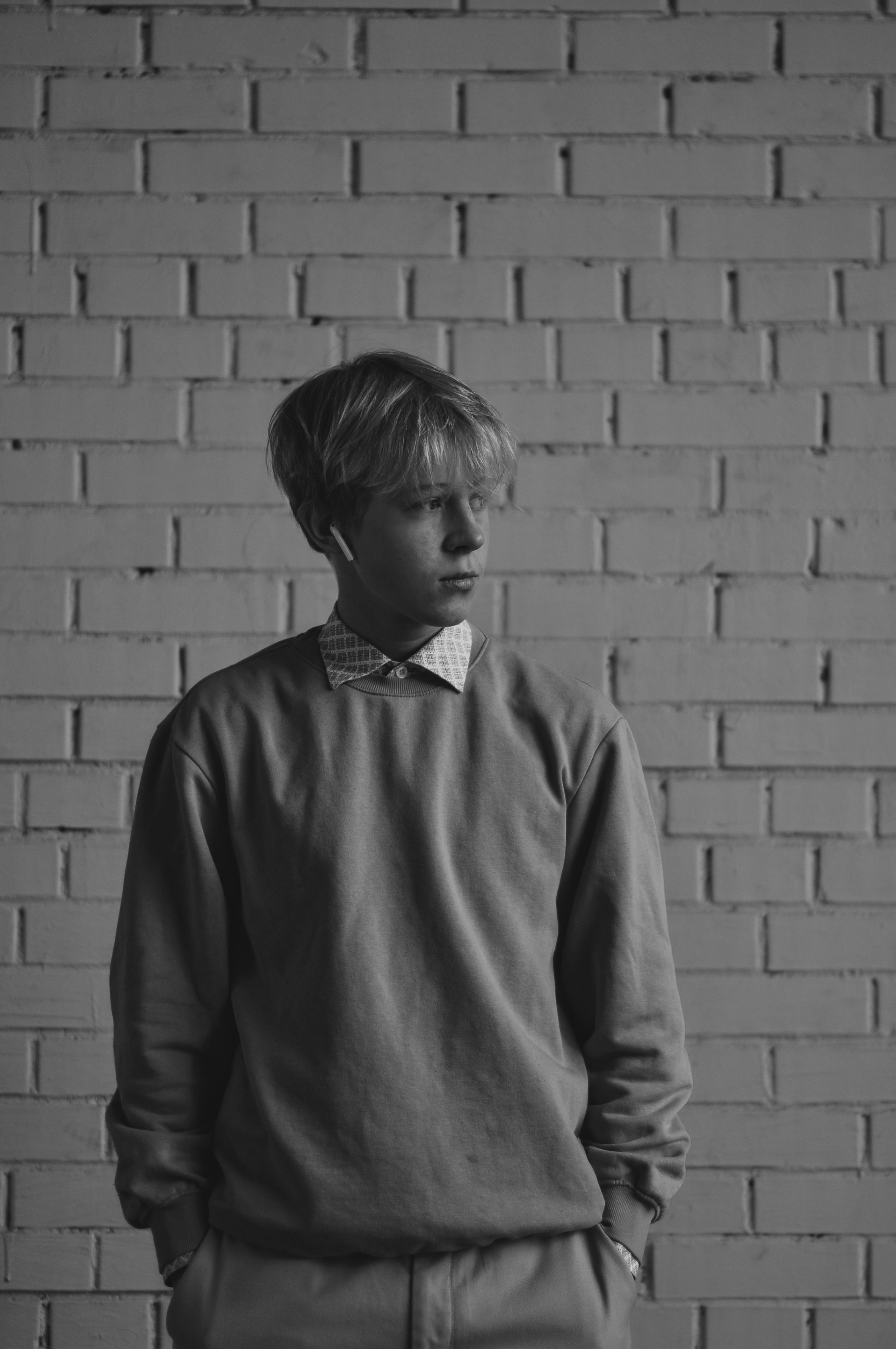 black and white picture of young boy standing in front of brick wall