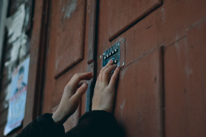 Close-up of hands pressing a keypad on a wooden door, showcasing security and access entry.