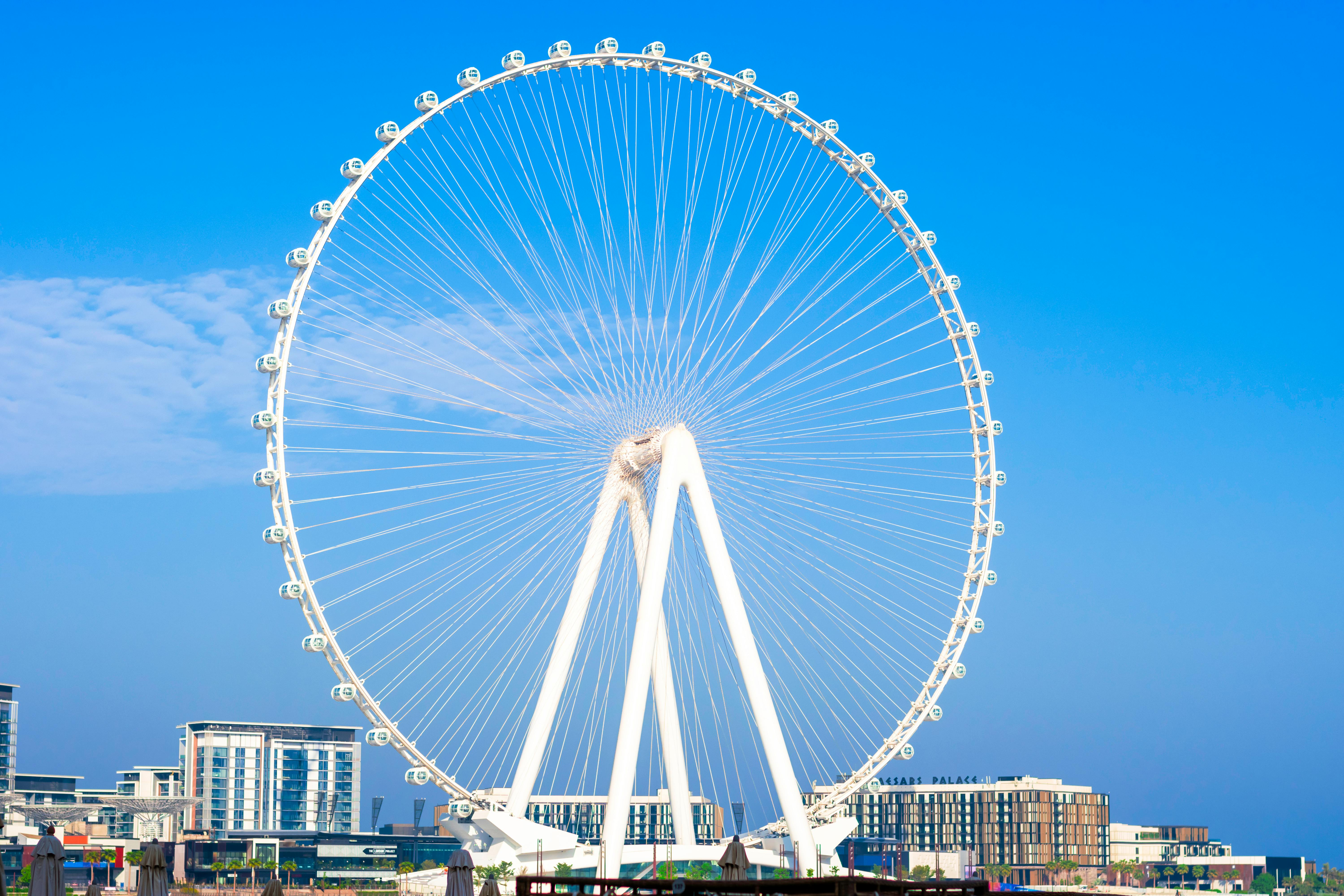 Stunning view of the Dubai Ferris Wheel set against a vivid blue sky, showcasing modern architecture