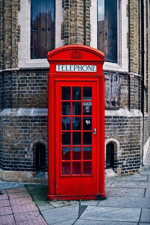 Free Red Telephone Booth near Brown Brick Wall Stock Photo