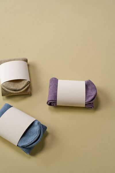 Folded ribbed crew socks with blank paper bands on a sand background — photo by Ron Lach on Pexels