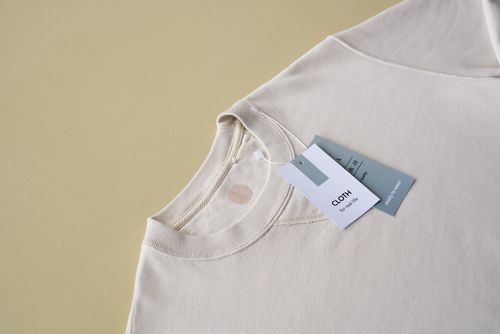 Free Minimalist beige sweatshirt displayed with tags on a yellow background, perfect for e-commerce. Stock Photo
