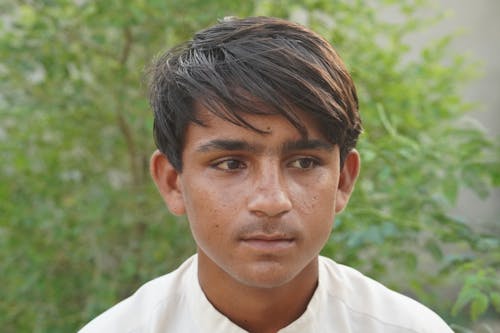 A Close-up Shot of a Young Boy in White Shirt