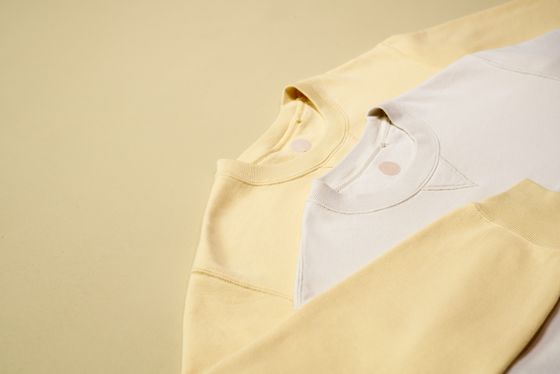 Butter-yellow and cream sweatshirts folded on a soft yellow ground, photo by Ron Lach on Pexels