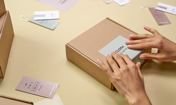 Hands packing a cardboard box with sustainable packaging