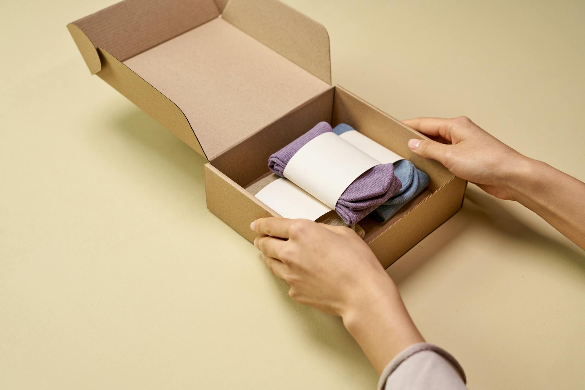 A Person Packaging Folded Socks with a Cardboard Box