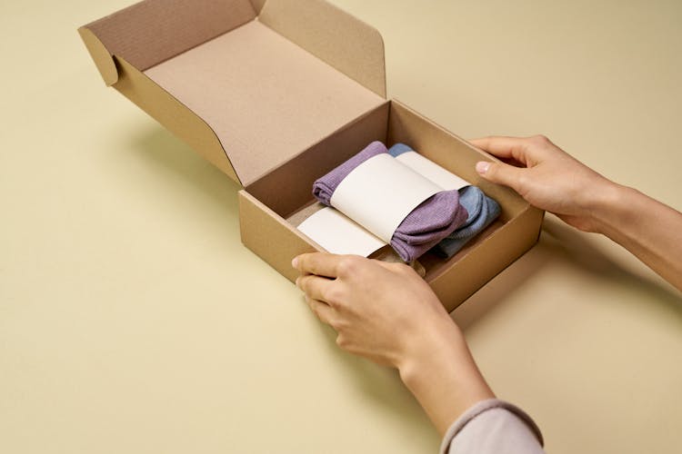 A Person Packaging Folded Socks With A Cardboard Box