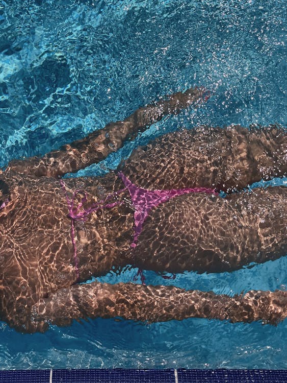 Woman in Pink Bikini Swimming in a Pool