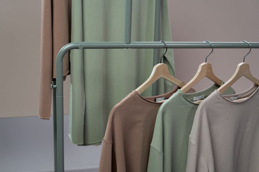 Earth-toned knits on wooden hangers in a studio — photo by Ron Lach on Pexels