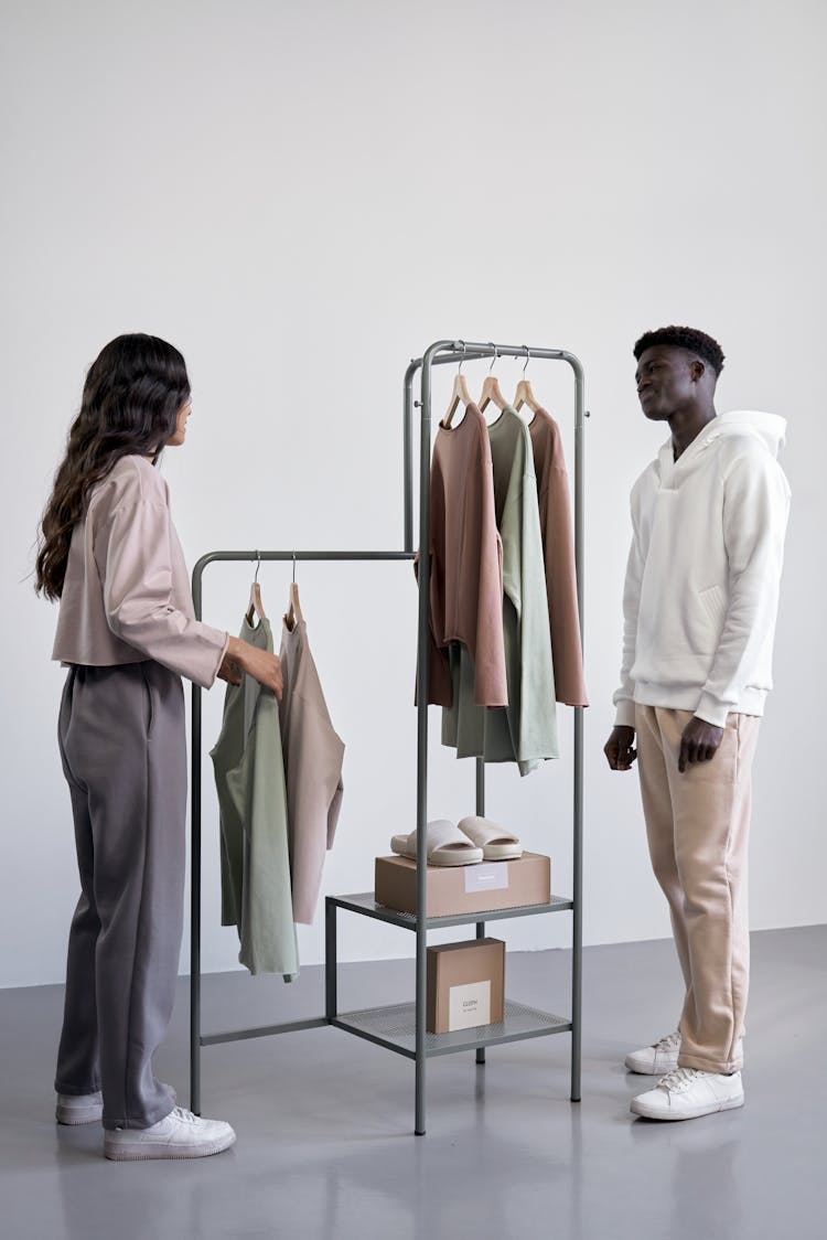 A Man And Woman Standing Near The Clothes Rack