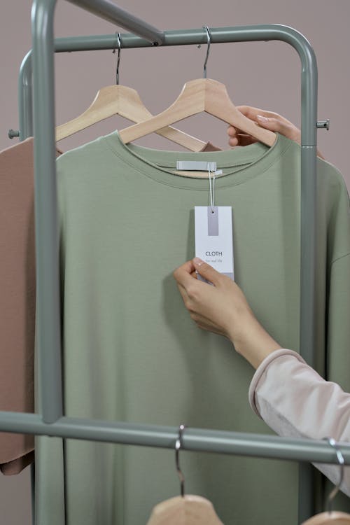 Person Holding White Clothes Hanger With Green Crew Neck Shirt