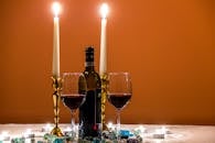 Two Almost Empty Long Stem Wine Glasses Beside Wine Bottle and Lighted Candles