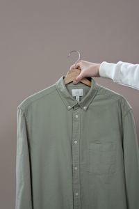Green shirt on a hanger against a neutral backdrop, photo by Ron Lach on Pexels