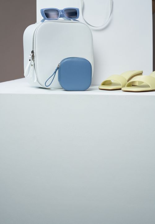 Free Stylish arrangement of a white backpack, sunglasses, and sandals on display. Stock Photo