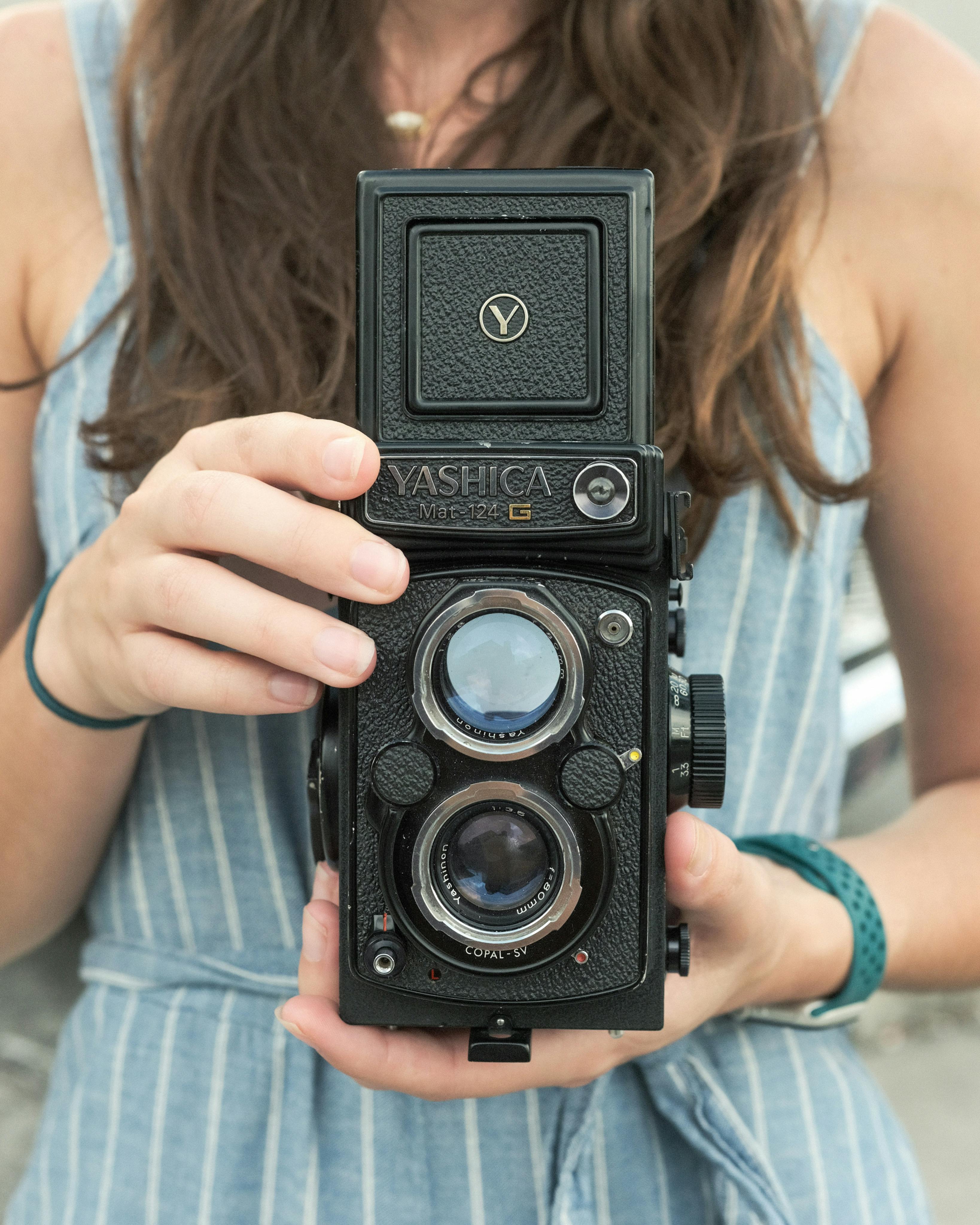 Close-up of a woman holding a vintage Yashica camera, highlighting photography nostalgia.