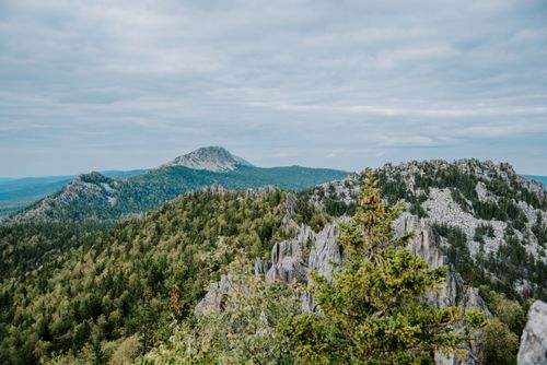 Free A breathtaking aerial shot capturing a scenic mountain range with lush forests and dramatic rock formations. Stock Photo