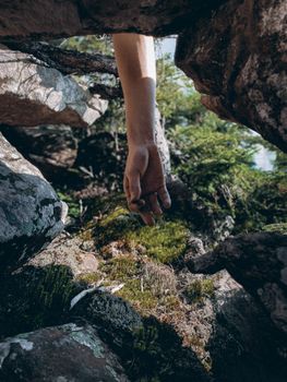 A mysterious hand extends through mossy rocks, creating a mystical outdoor scene.