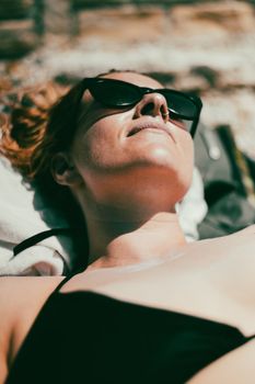 Relaxing summer sunbathing scene in Poreč, Croatia featuring a woman with sunglasses.