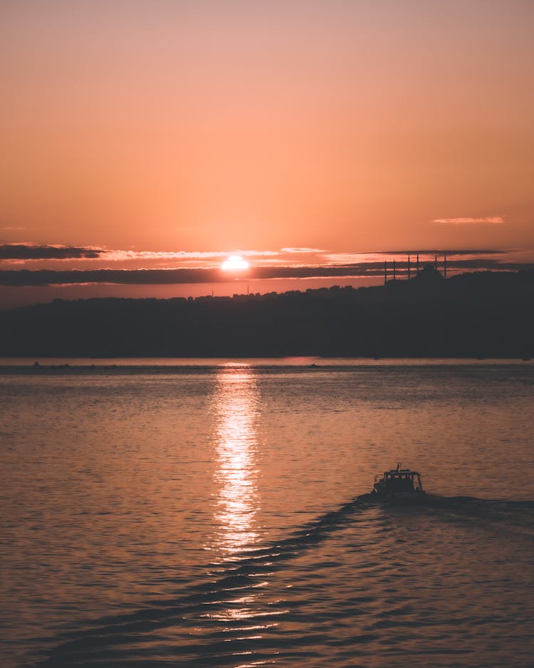 Boat Sailing On Water At Sunset