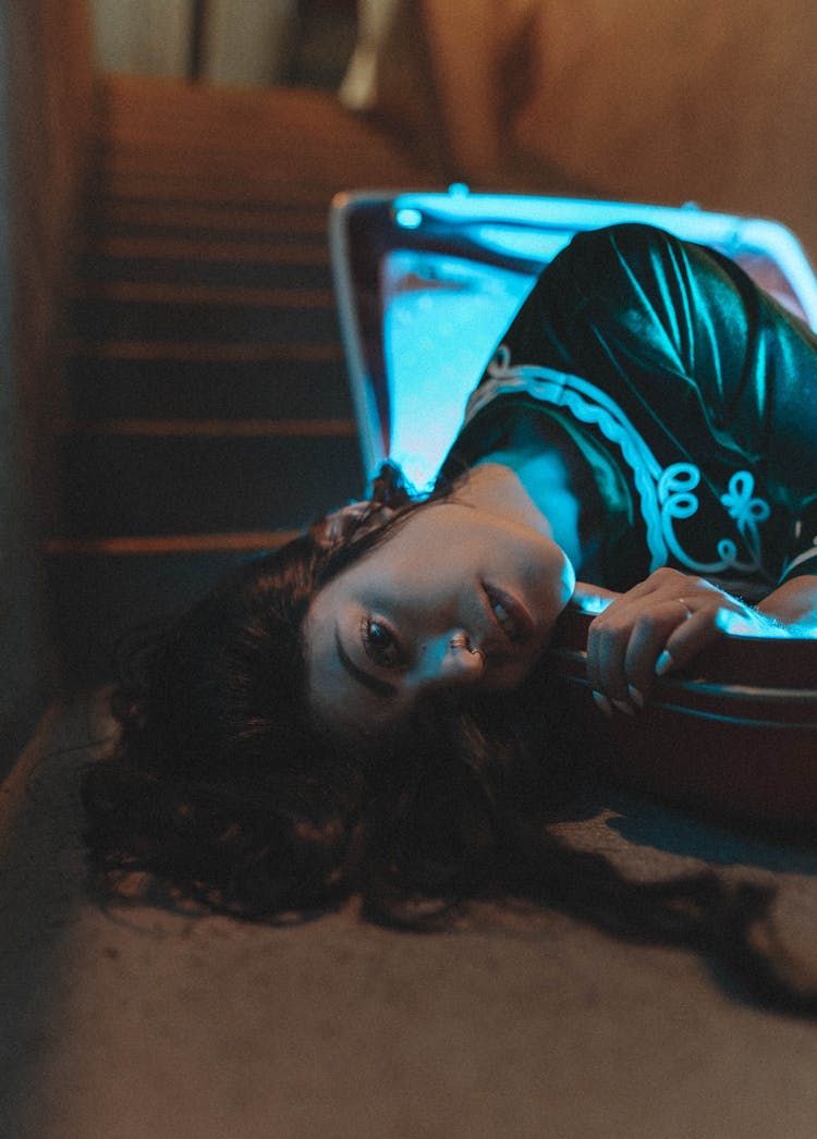 Woman Laying Down On Illuminated Box On Floor