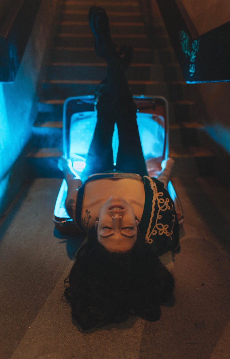 Woman Laying Down On Illuminated Box On Floor With Legs Raised