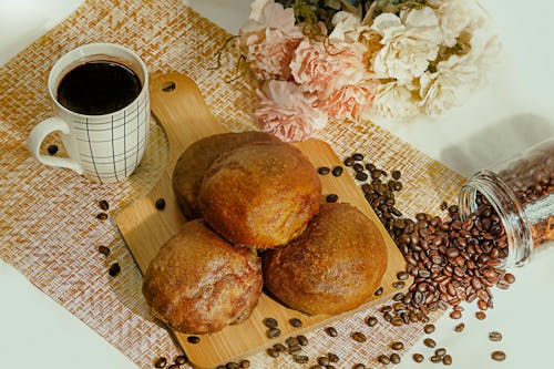 Close-Up Shot of Breads on a Wooden Chopping Board beside a Cup of Coffee