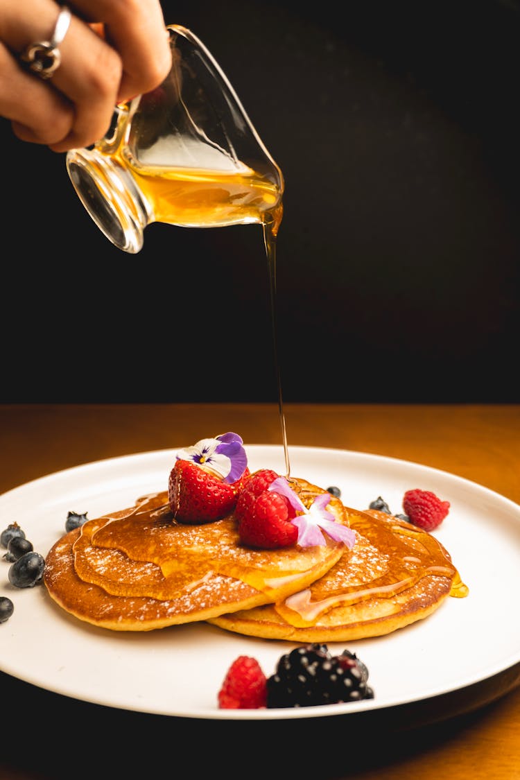 Hand Pouring Honey On Pancakes