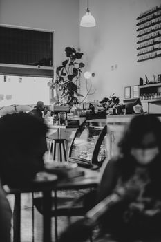 A black and white photo of a cozy urban café with people enjoying a relaxed atmosphere.