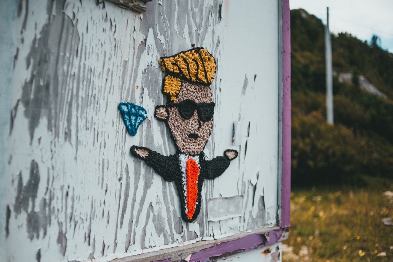 image of a knitted cartoon figure on a worn wall in an outdoor setting