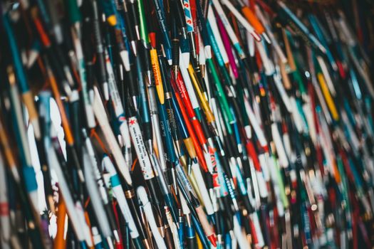 Close-up of a vibrant and diverse collection of pens hanging together, showcasing various brands and colors.