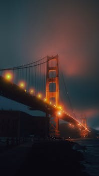 A misty, atmospheric view of the illuminated Golden Gate Bridge at night.