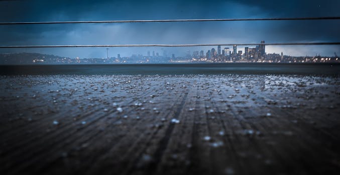 Dramatic Seattle skyline at night under a rainy, cloudy sky featuring the iconic Space Needle.