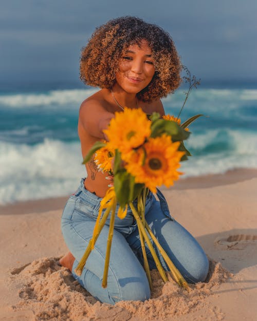 Shirtless Woman Holding a Bouquet of Sunflowers