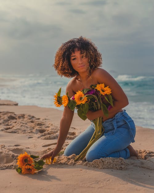 Woman with Flowers Kneeling in the Sand 